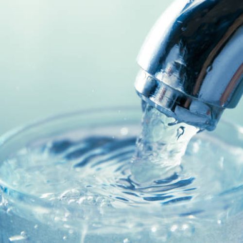 close-up view of water flowing from tap into glass