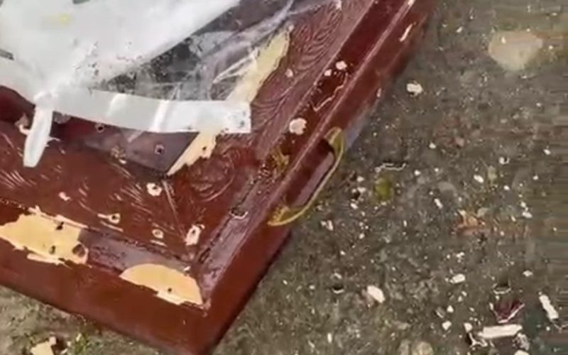 Homens metralham caixão com defunto dentro.